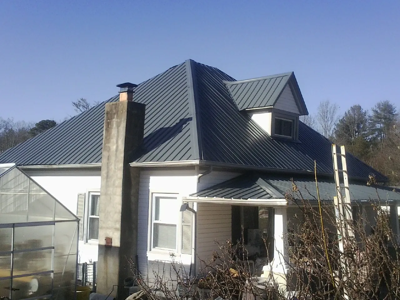 Dark blue standing seam metal roof on a white farmhouse with dormer — Slate & Tile Roof Repair by Roofing Brothers in Salkum