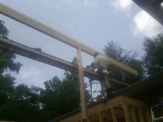 Carpenter setting a ridge beam over a new addition frame — Ice Dam Removal by Roofing Brothers in Salkum