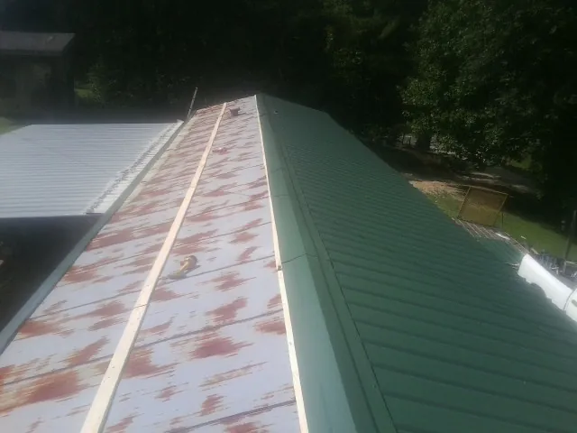 Old rusted panels beside newly installed green metal roofing in Salkum