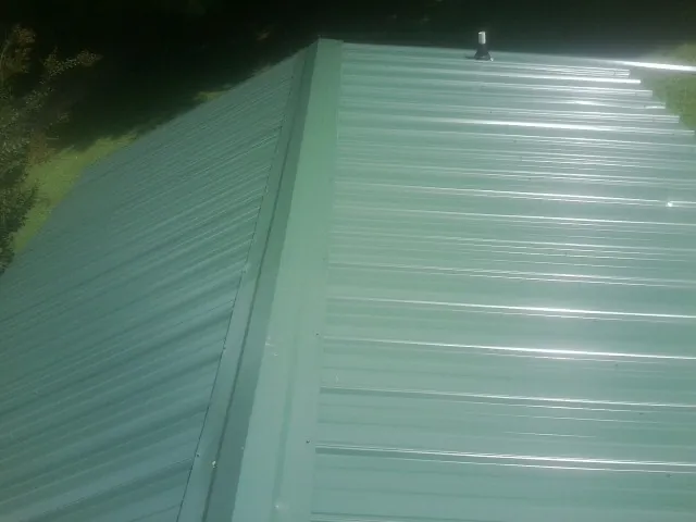 New green metal panels meeting at the ridge of a roof — Flat Roof Repair work by our crew in Salkum