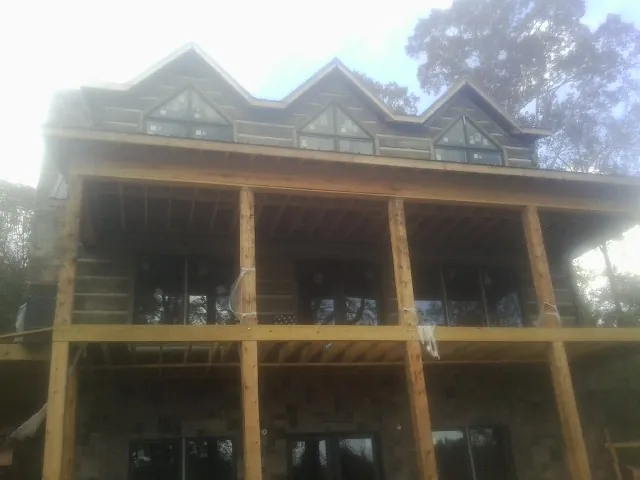 Dormers and porch framing on a large log home under construction — Roof Coating work by our crew in Salkum