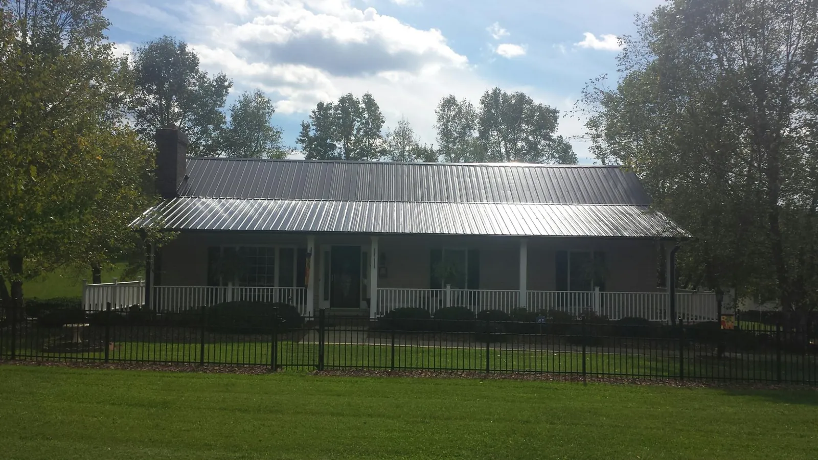 Gray metal roof on a brick ranch with a full width front porch — Gutter Guard Installation work by our crew in Salkum