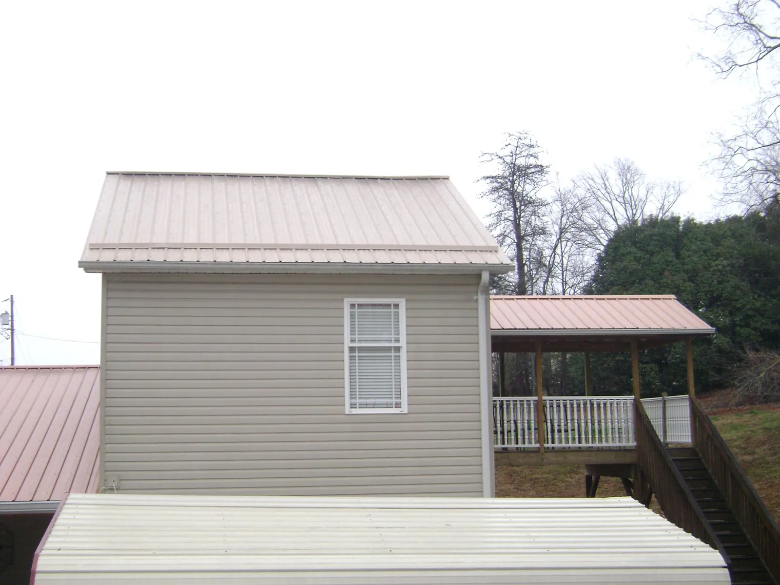 Tan metal roofs on a two story addition and attached porch, from a Roof Replacement job in Salkum
