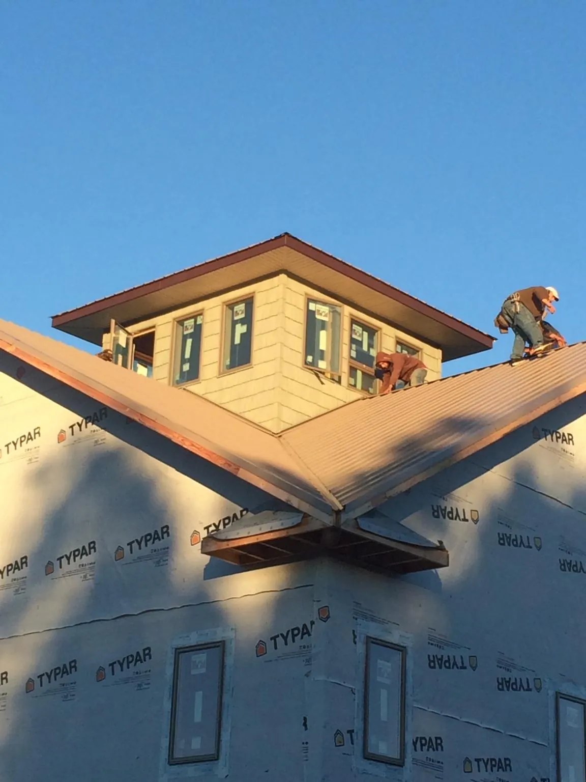 Roofers working around a rooftop cupola on a new metal roof at sunset — Roof Waterproofing in Salkum by Roofing Brothers